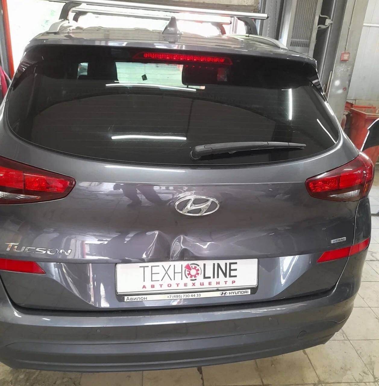 Hyundai Tucson на осмотре повреждений кузова. Повреждена задняя дверь, камера заднего вида и кнопка открытия багажника зажаты в поврежденном металле, но работают